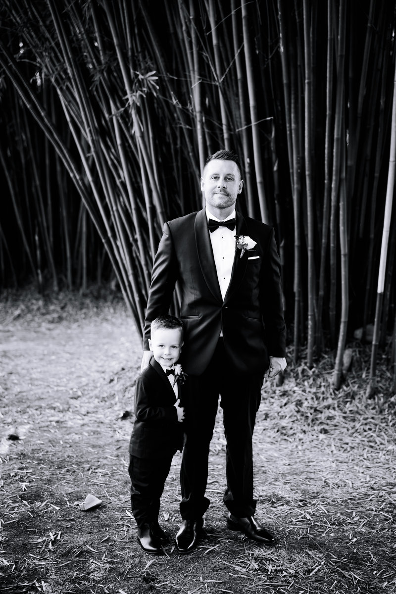 black and white portrait of groom and son in front of bamboo